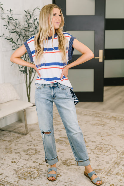 Woman wearing a striped shirt and jeans standing indoors.