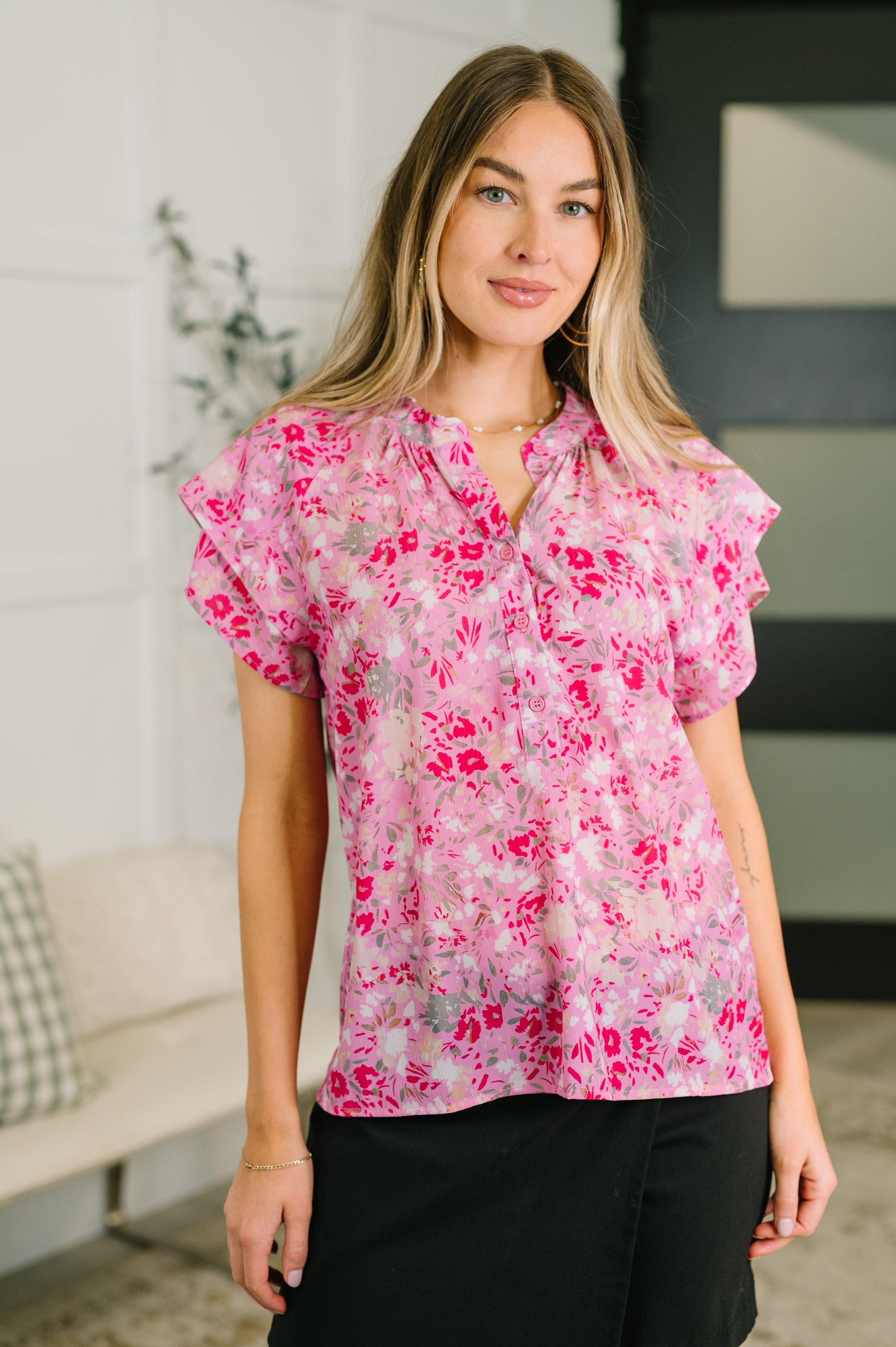 Woman wearing a pink floral blouse in an indoor setting