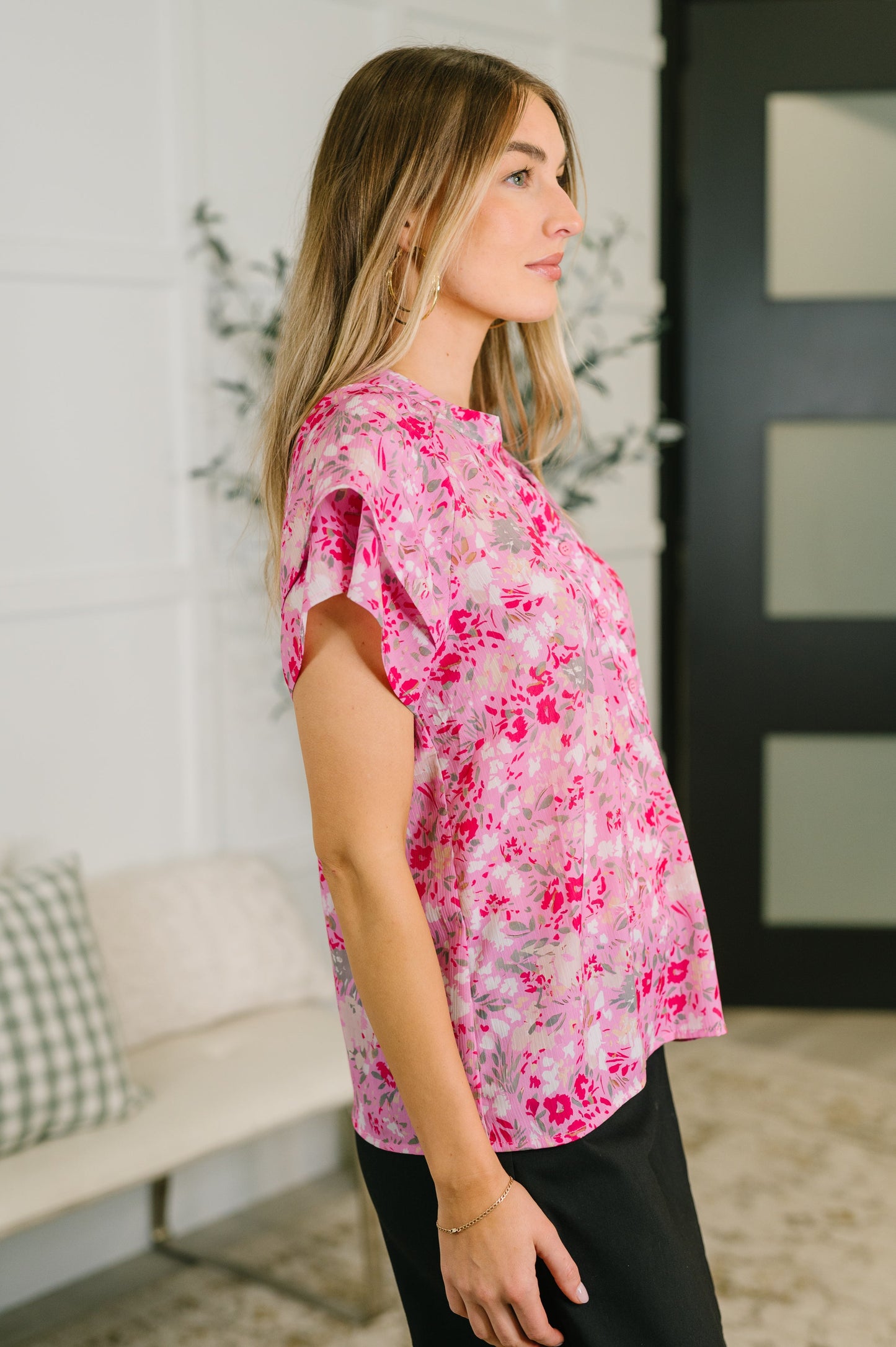 Woman wearing a pink floral blouse in a living room setting
