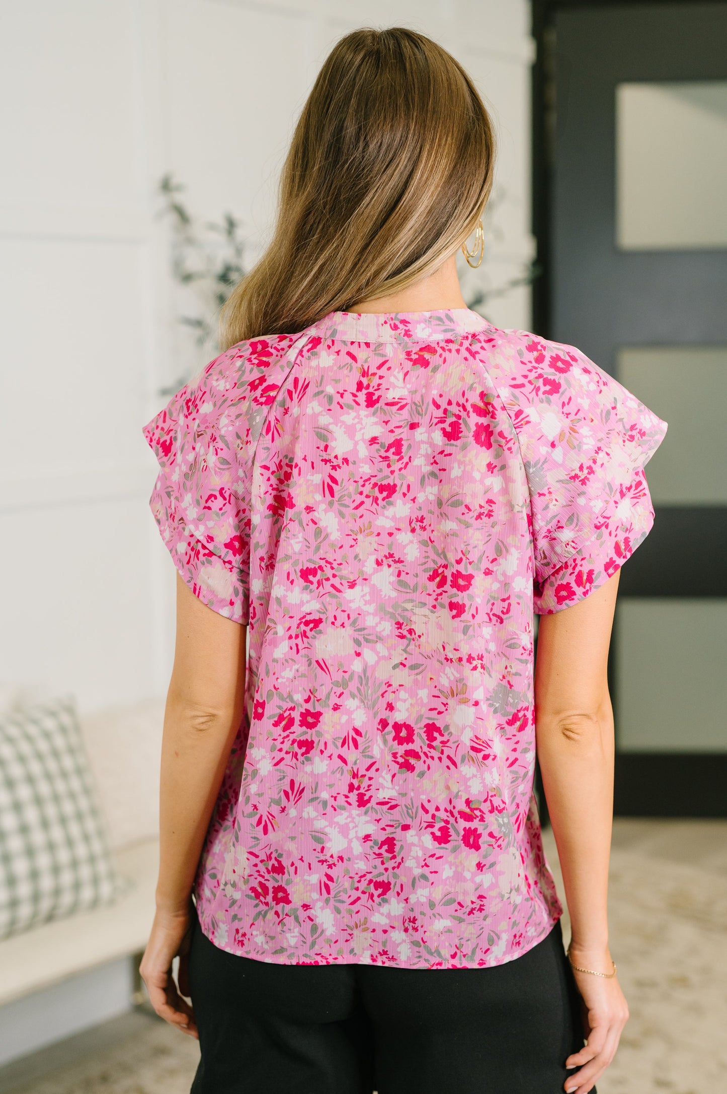Woman wearing a pink floral blouse in an indoor setting