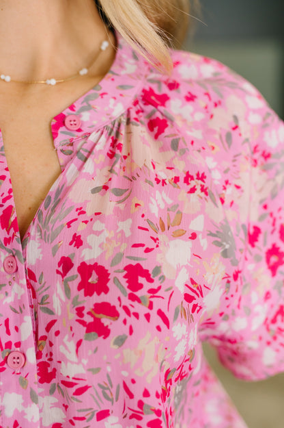 Close-up of a person wearing a pink floral blouse with a blurred background