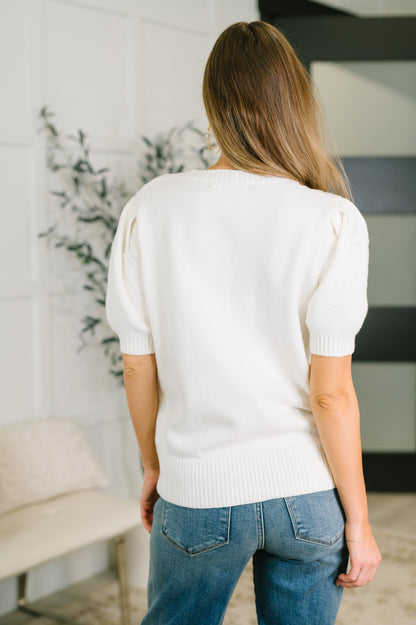 Woman wearing a white sweater and blue jeans in an indoor setting