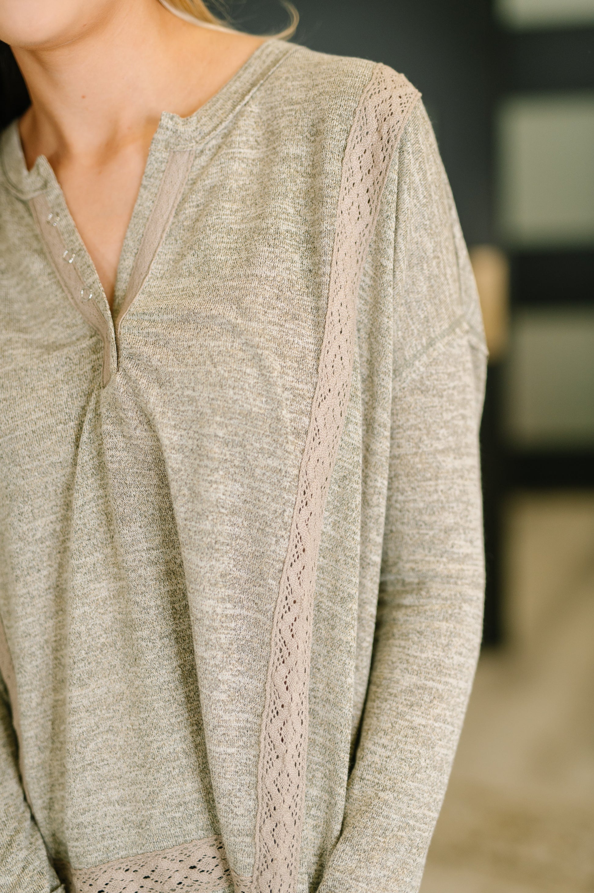Close-up of a person wearing a light brown long-sleeve top with lace trim.