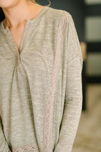 Close-up of a person wearing a light brown long-sleeve top with lace trim.
