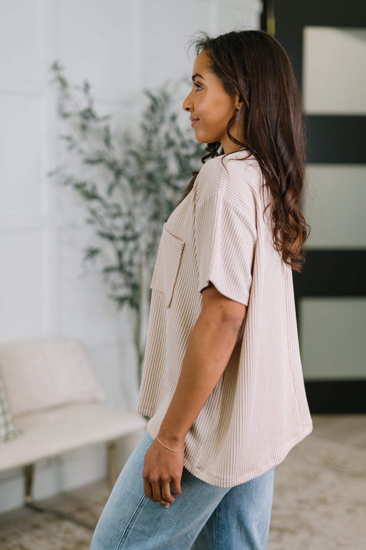 Woman wearing a light-colored blouse and blue jeans in an indoor setting