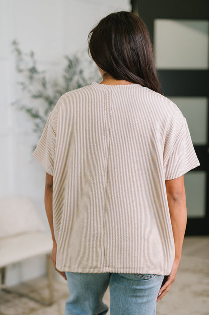 Person wearing a beige ribbed sweater in an indoor setting