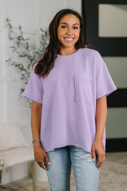 Woman wearing a purple oversized shirt with a pocket in a casual setting.