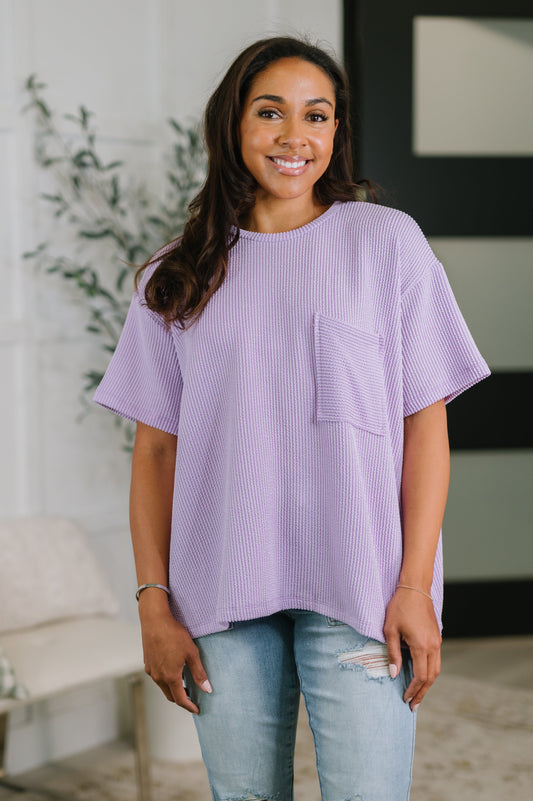 Woman wearing a purple oversized shirt with a pocket in a casual setting.