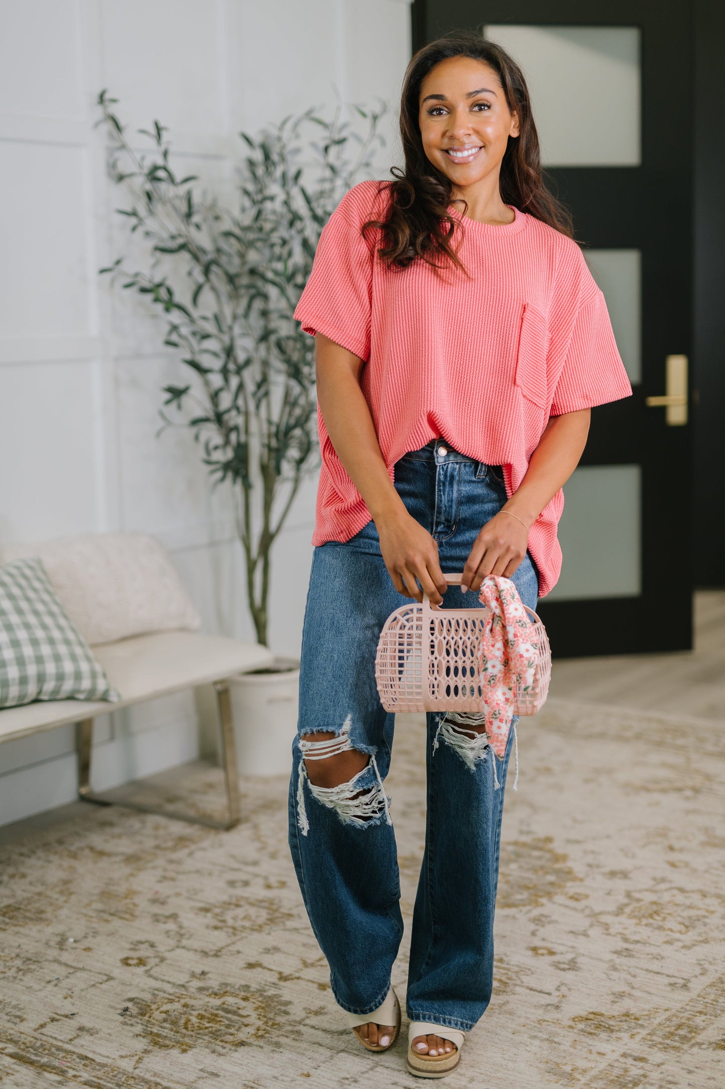 Woman holding a pink handbag in a living room setting