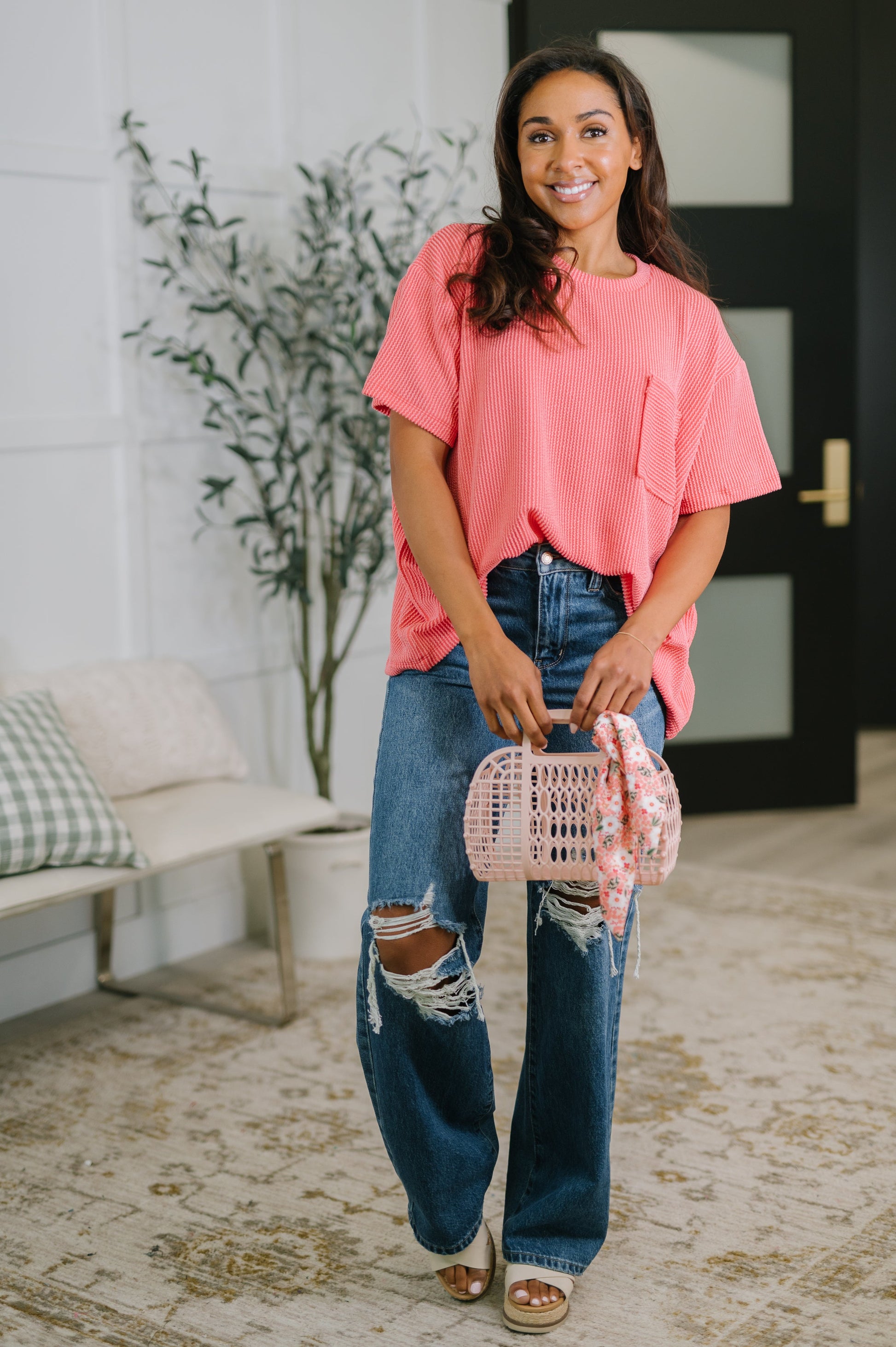 Woman holding a pink handbag in a living room setting
