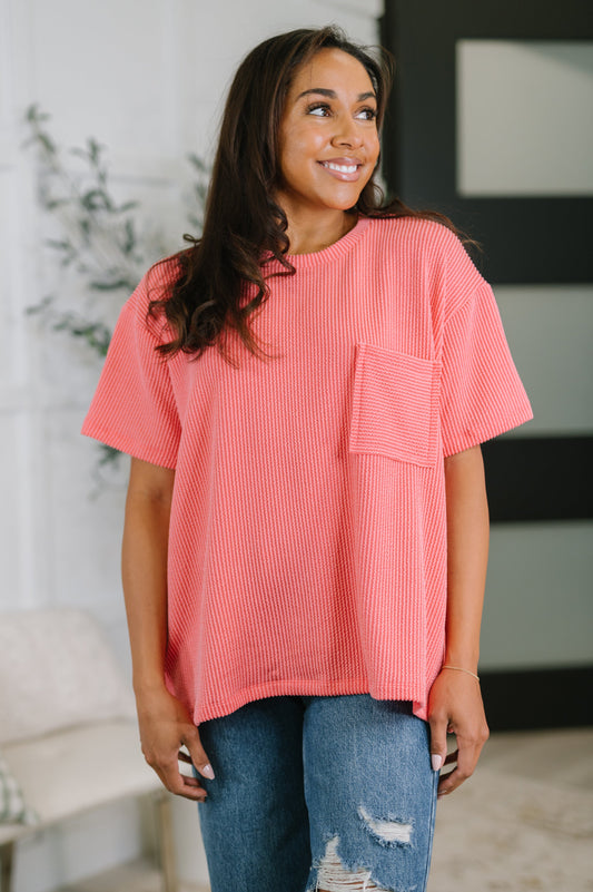 Woman wearing a coral oversized t-shirt with a pocket in a casual setting.