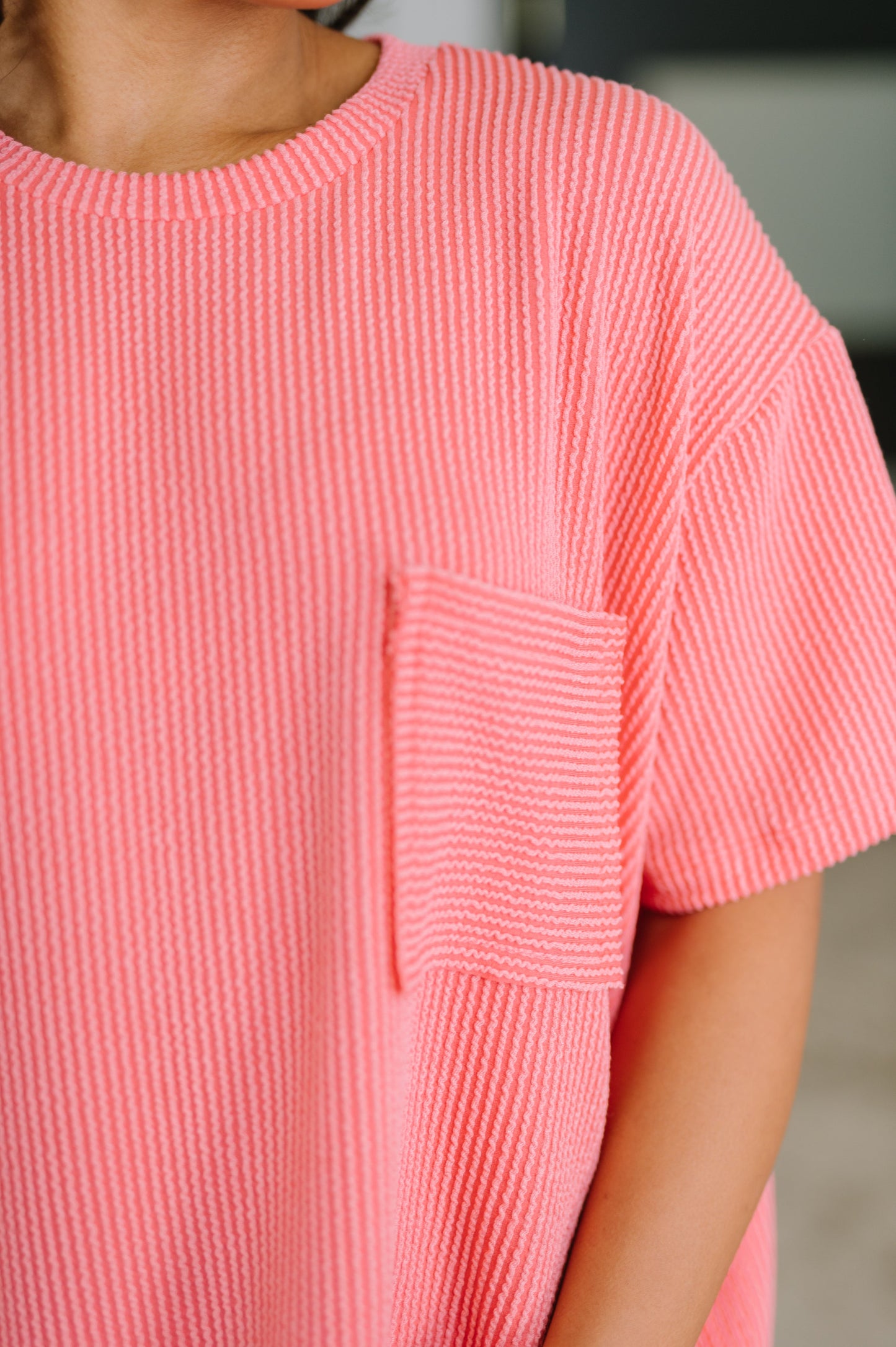 Close-up of a person wearing a pink textured dress with a pocket.