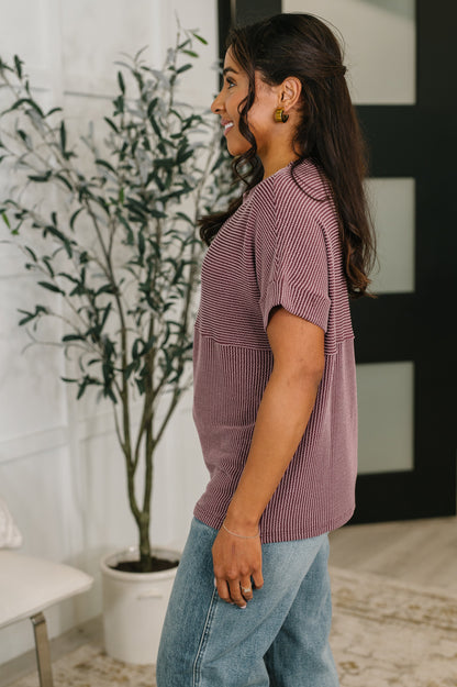 Woman wearing a striped shirt and jeans standing in a room with a plant and abstract wall art.
