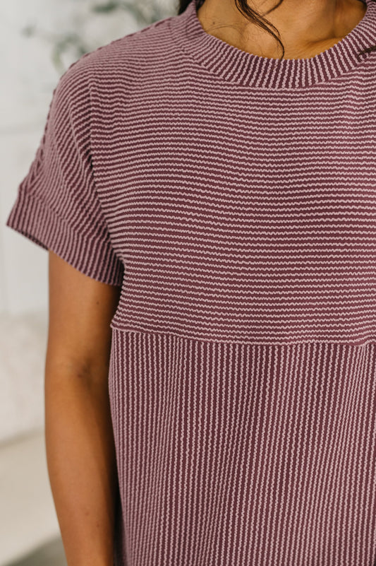 Close-up of a person wearing a maroon and white striped dress with a blurred background
