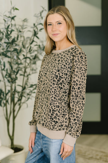Woman wearing a leopard print sweater in an indoor setting