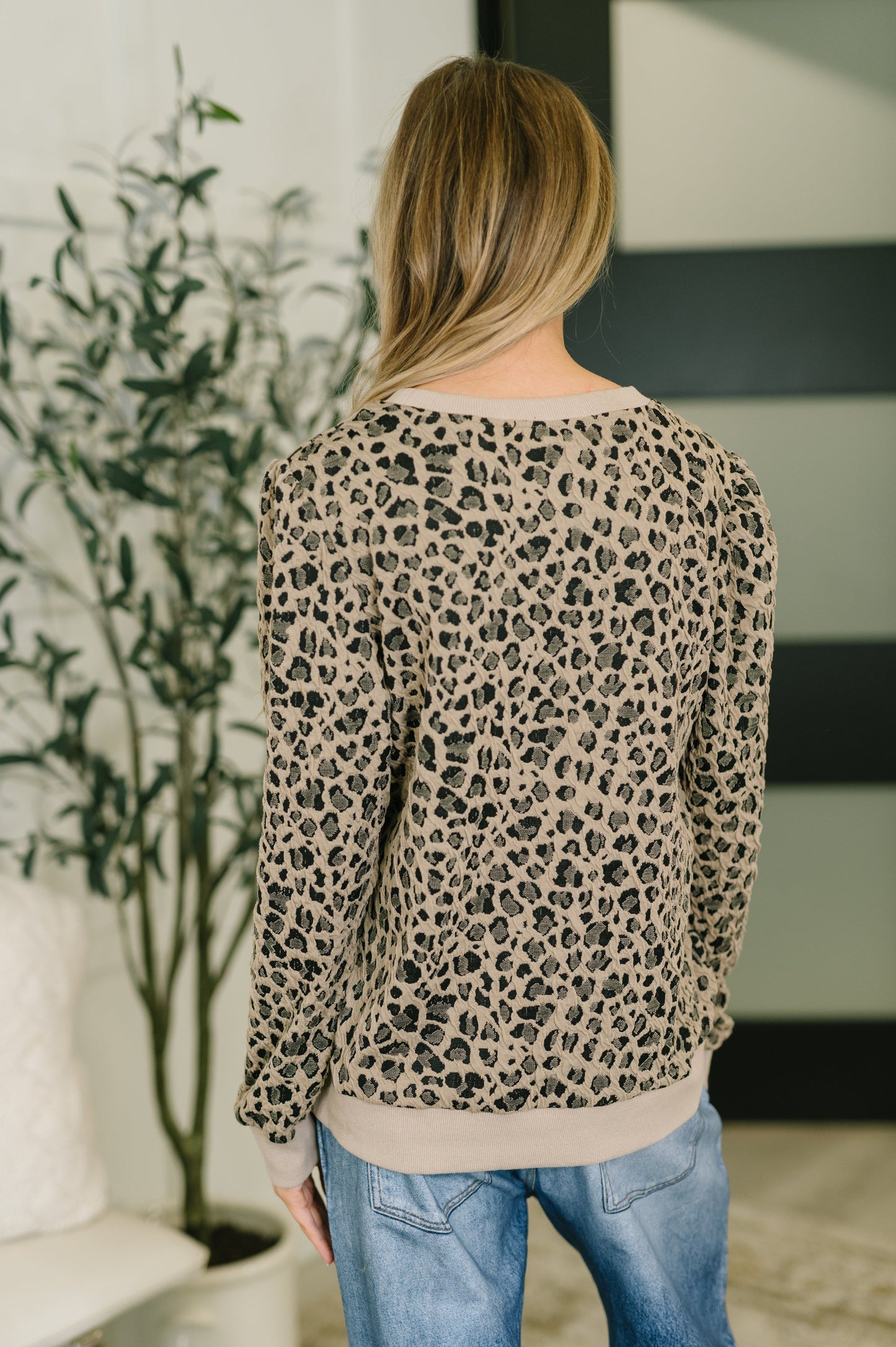 Person wearing a leopard print sweater in an indoor setting