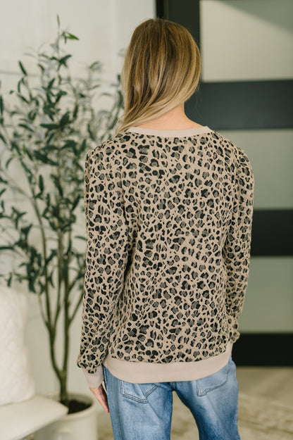 Person wearing a leopard print sweater in an indoor setting
