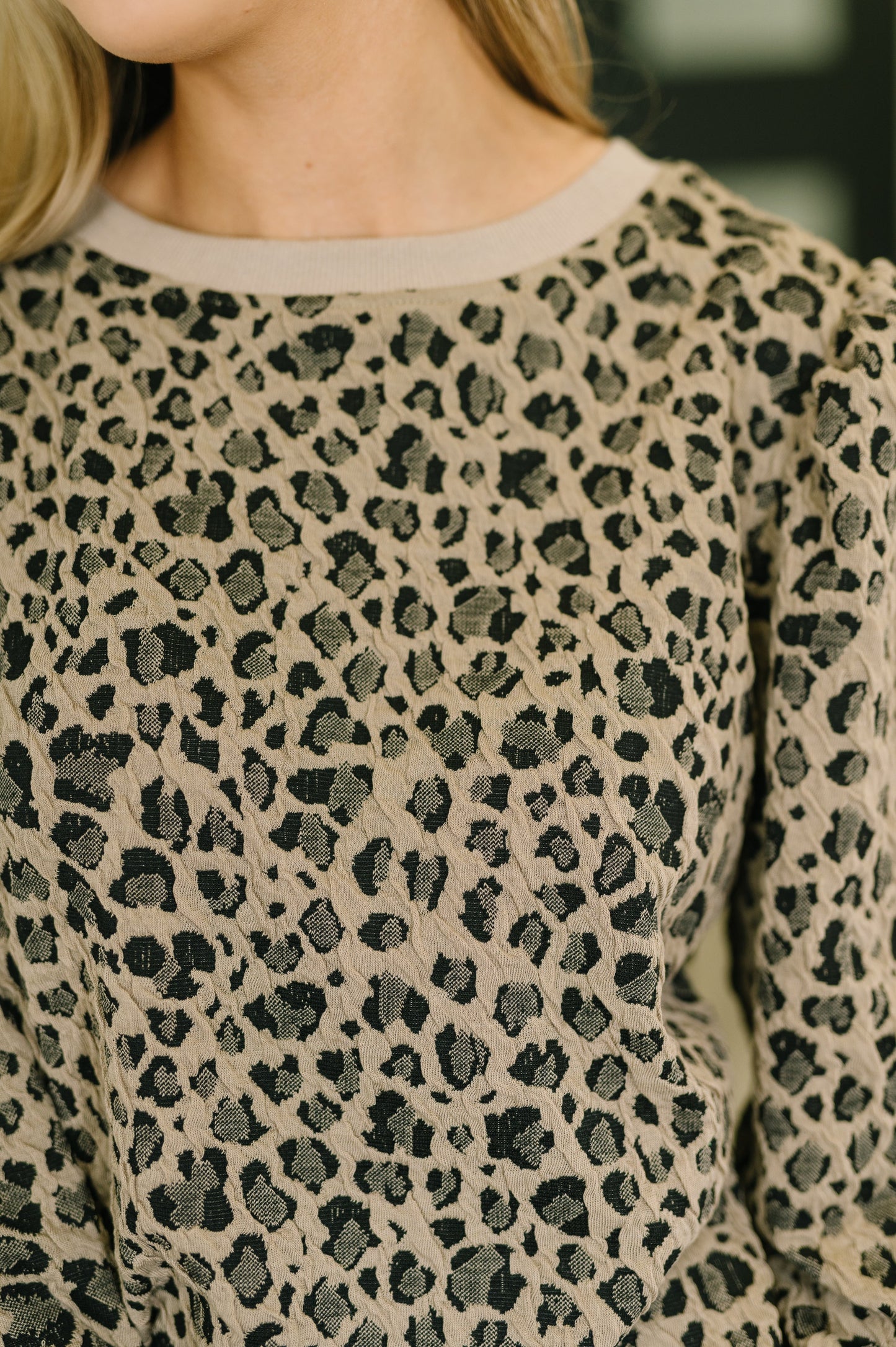 Close-up of a person wearing a leopard print sweater with a blurred background