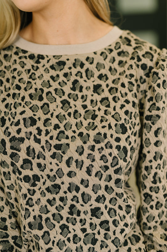 Close-up of a person wearing a leopard print sweater with a blurred background