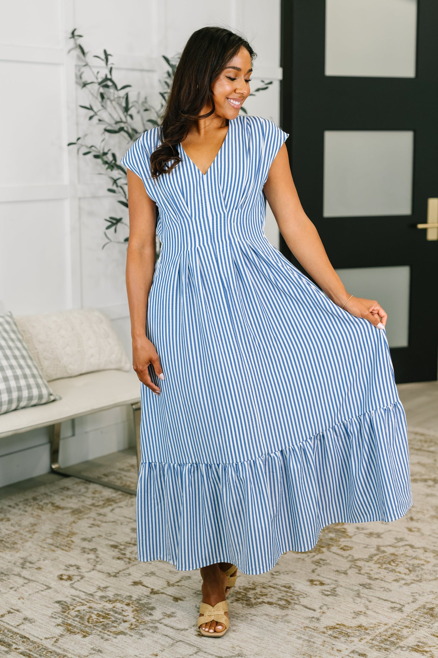 Woman wearing a blue and white striped dress in a living room setting.