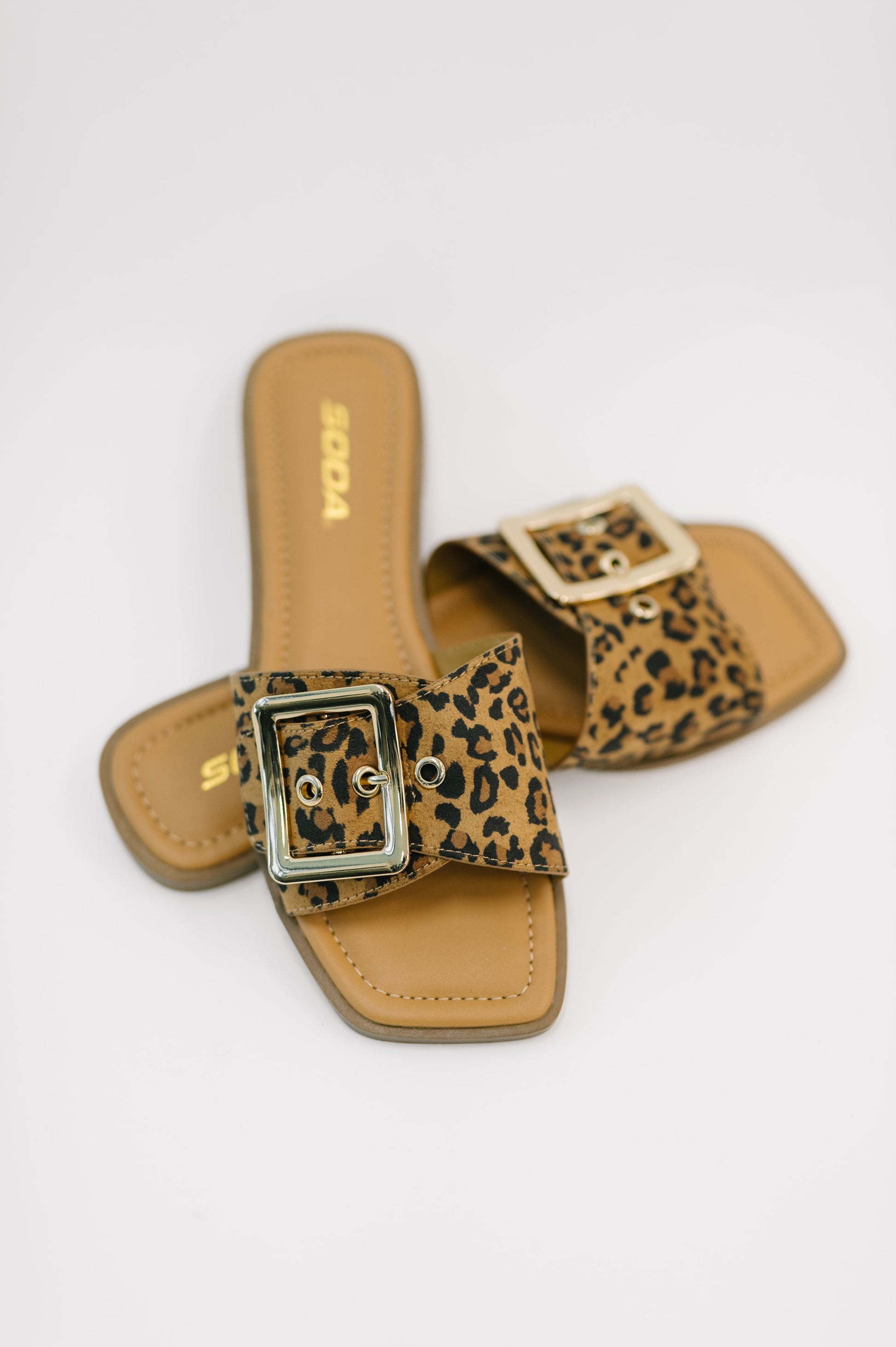 Pair of leopard print slide sandals on a white background