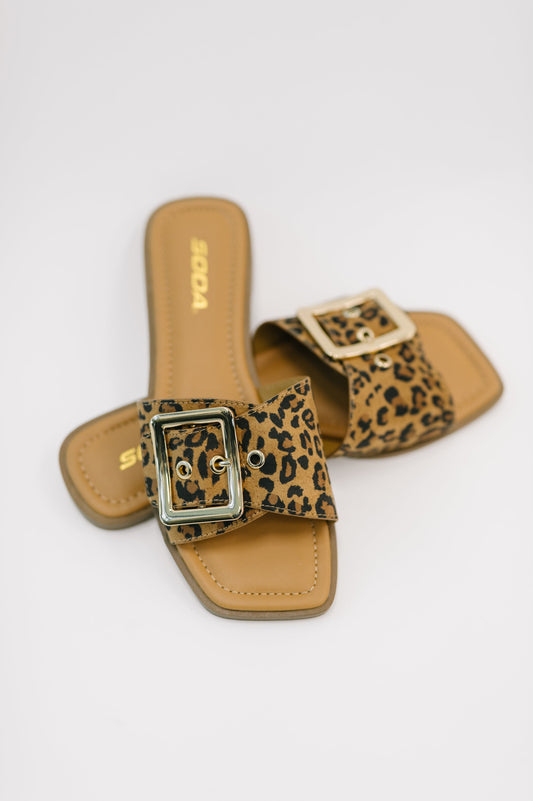 Pair of leopard print slide sandals on a white background