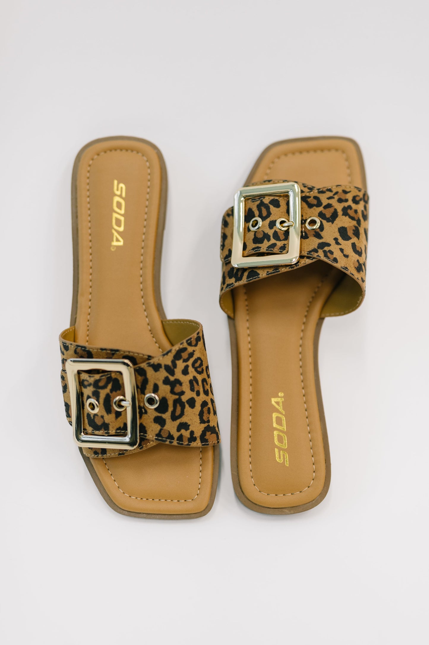 Pair of leopard print sandals with a buckle on a white background