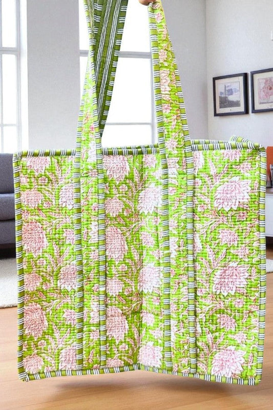 Green and pink floral patterned tote bag on a wooden surface with a neutral background
