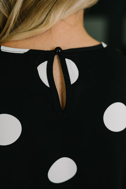 Black dress with white polka dots and a unique cutout design on the back.