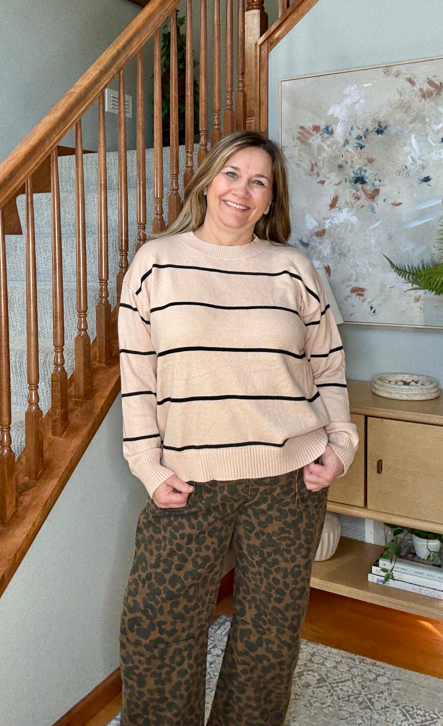 Woman wearing tan and black striped sweater with animal print wide leg cropped jeans