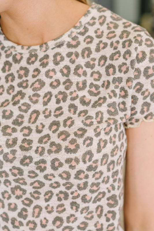 Close-up of a person wearing a leopard print top with a neutral background