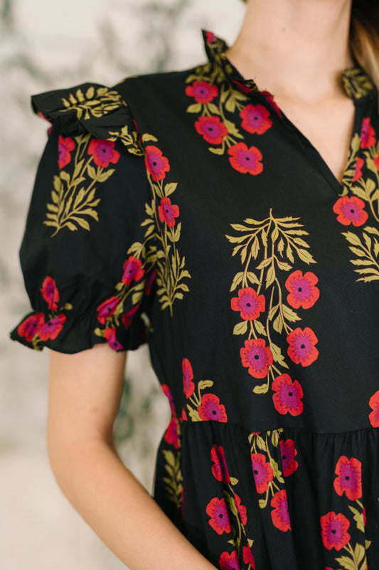 Black dress with colorful floral embroidery on a blurred background