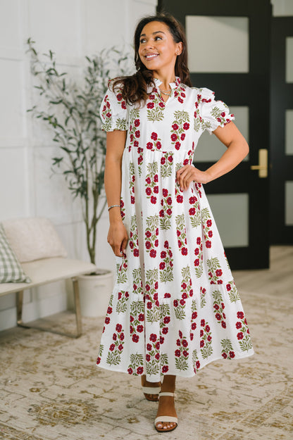 Woman wearing a white dress with red floral pattern indoors.