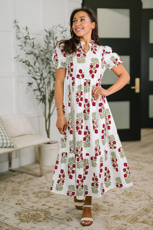 Woman wearing a white dress with red floral pattern indoors.