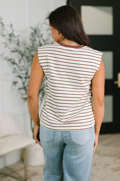 Woman wearing a striped sleeveless top and jeans in an indoor setting