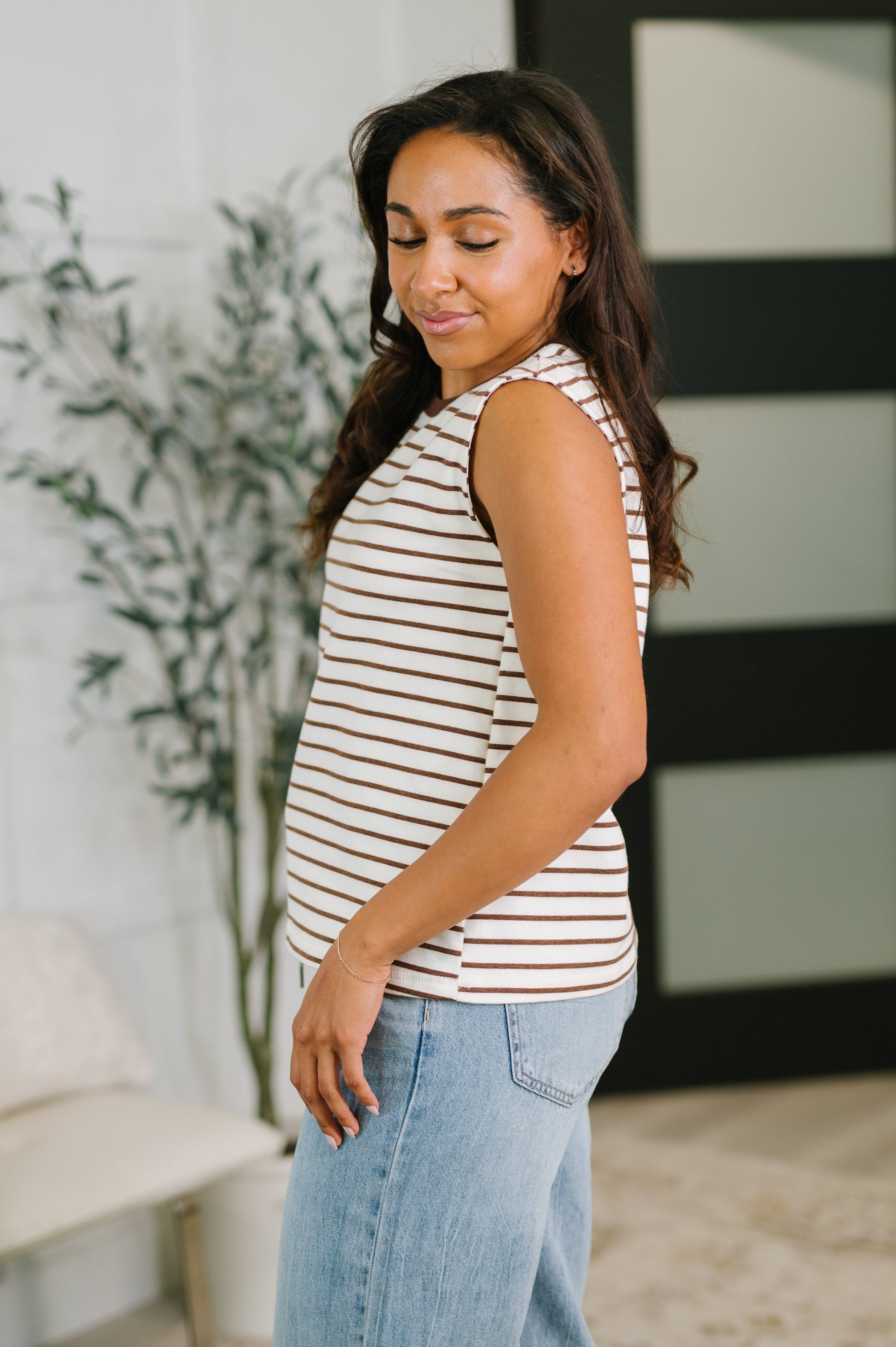 Woman wearing a striped tank top and jeans in an indoor setting