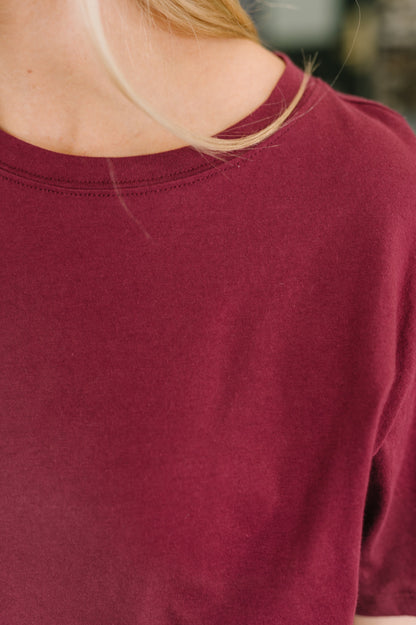 Close-up of a person wearing a maroon long-sleeve shirt with a blurred background