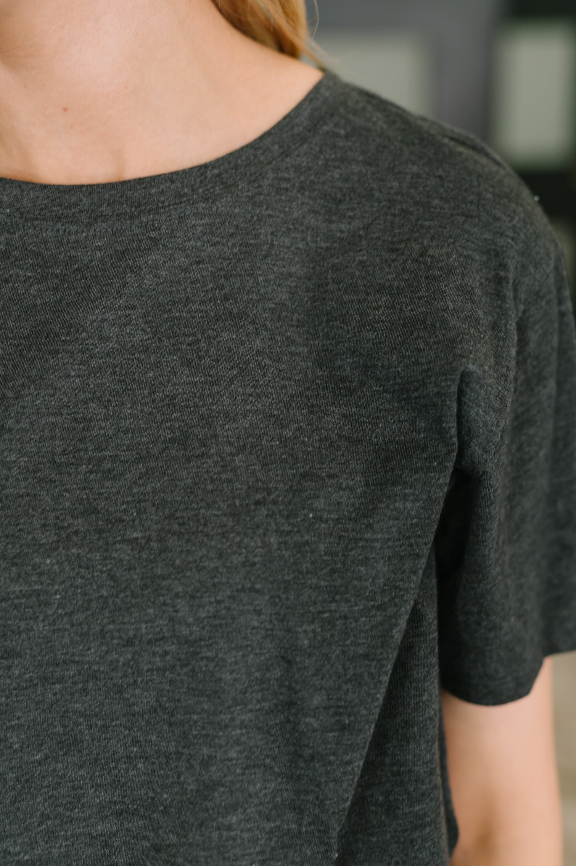 Dark gray t-shirt worn by a person with a blurred background