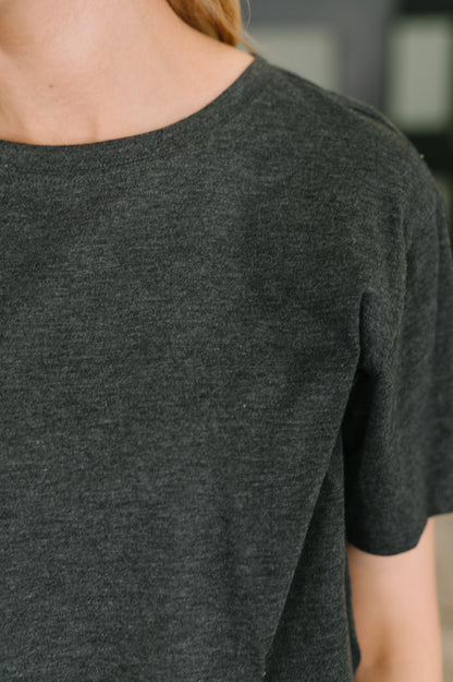 Dark gray t-shirt worn by a person with a blurred background