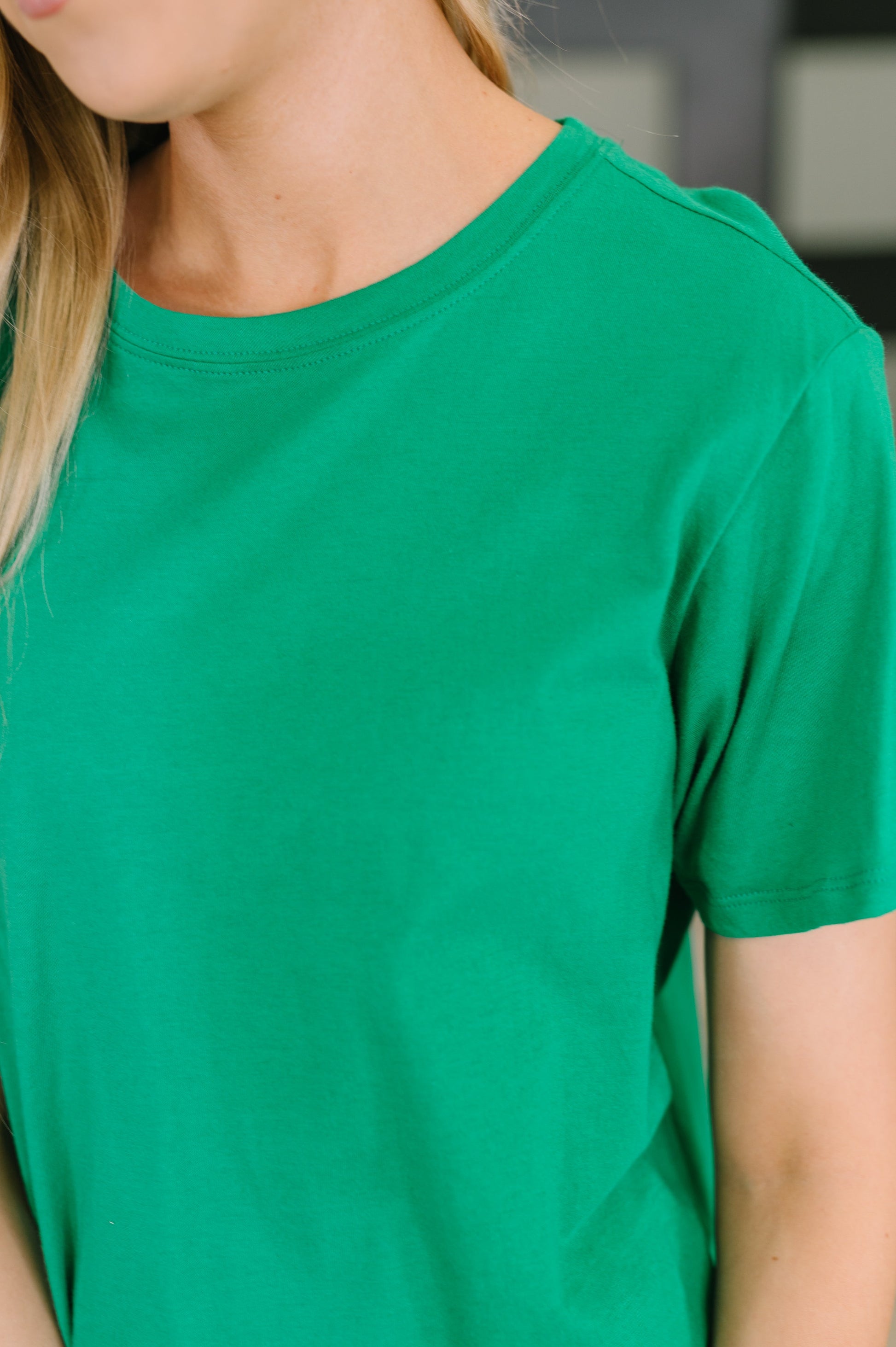 Green t-shirt worn by a person with a blurred background