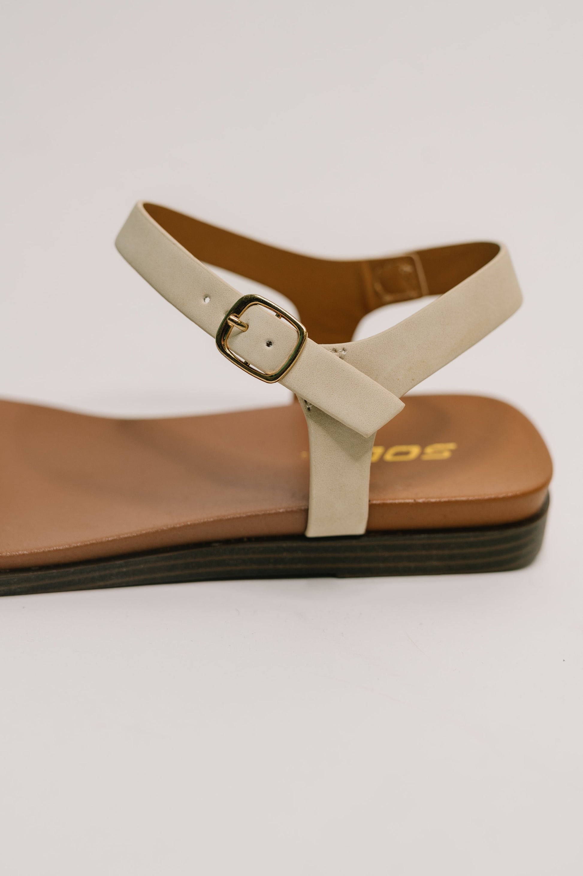 Beige sandal with a brown sole on a light gray background