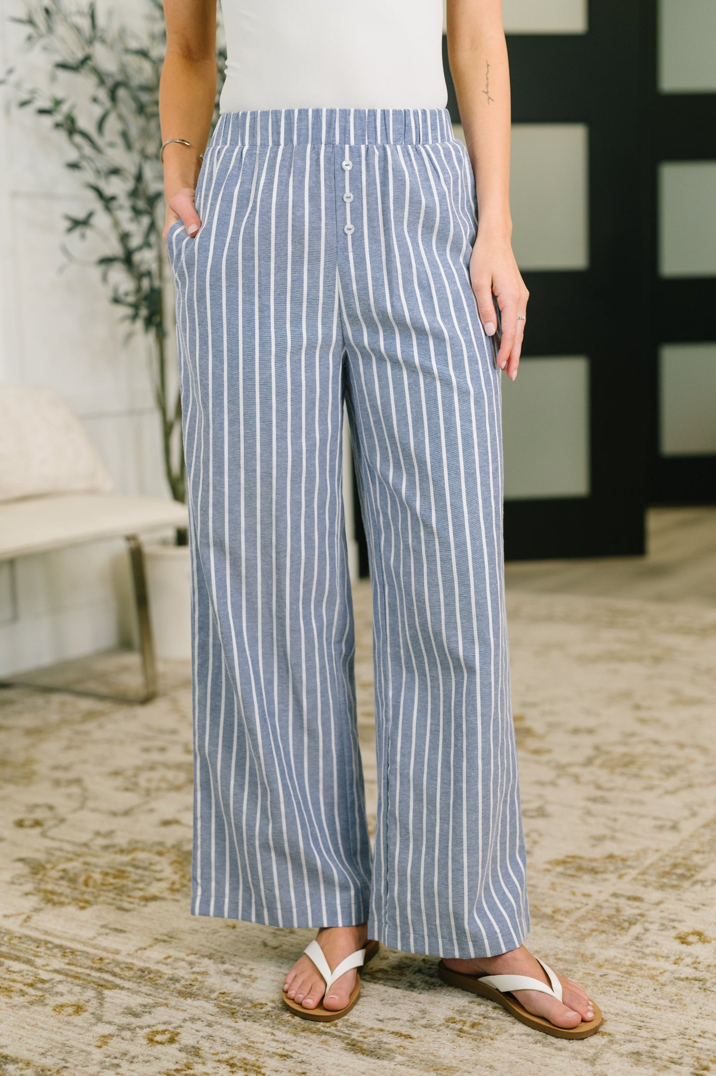 Person wearing blue and white striped pants standing indoors.