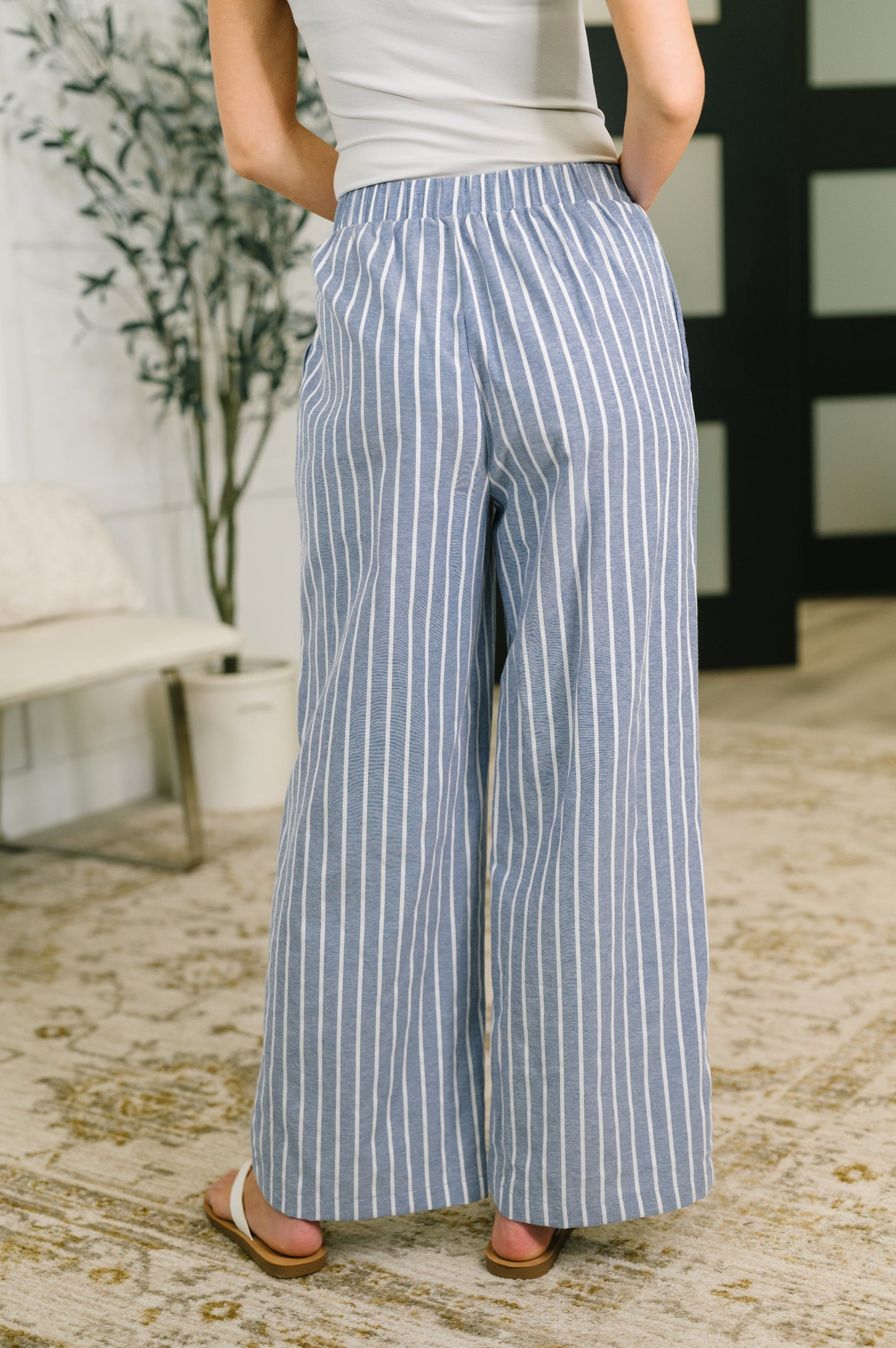 Person wearing blue and white striped wide-leg pants indoors.
