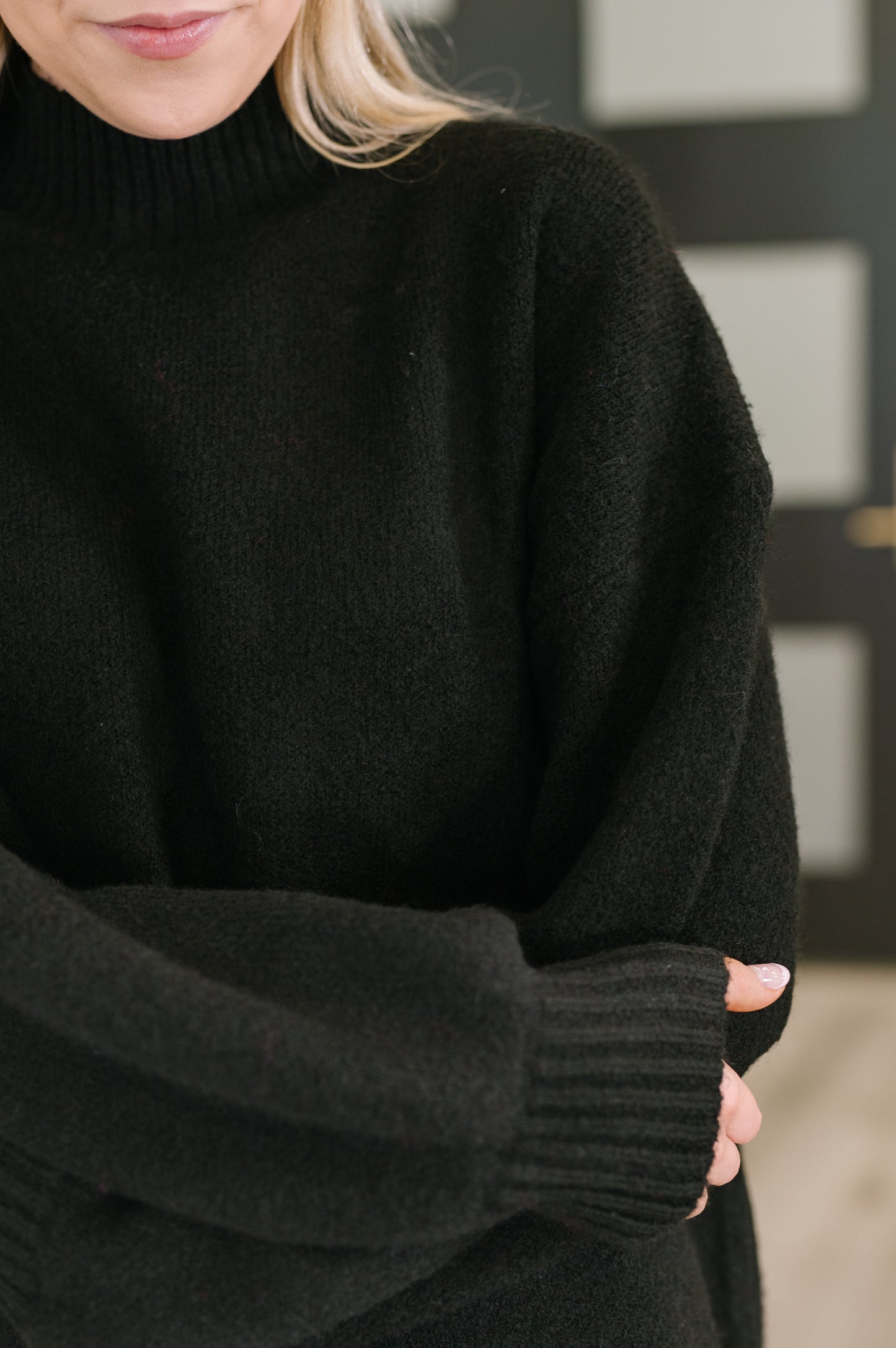 Person wearing a black sweater with a blurred background