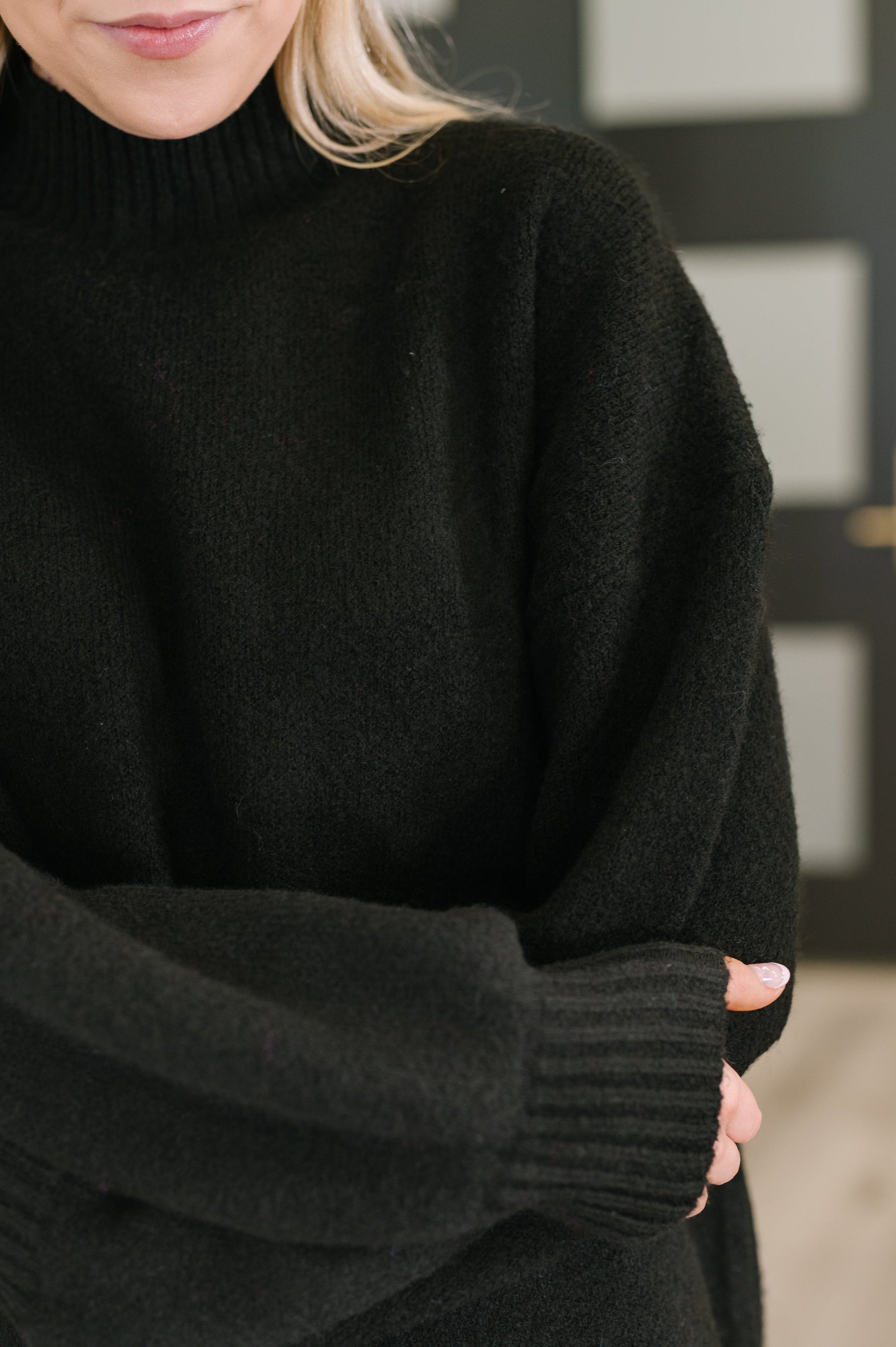 Person wearing a black sweater with a blurred background