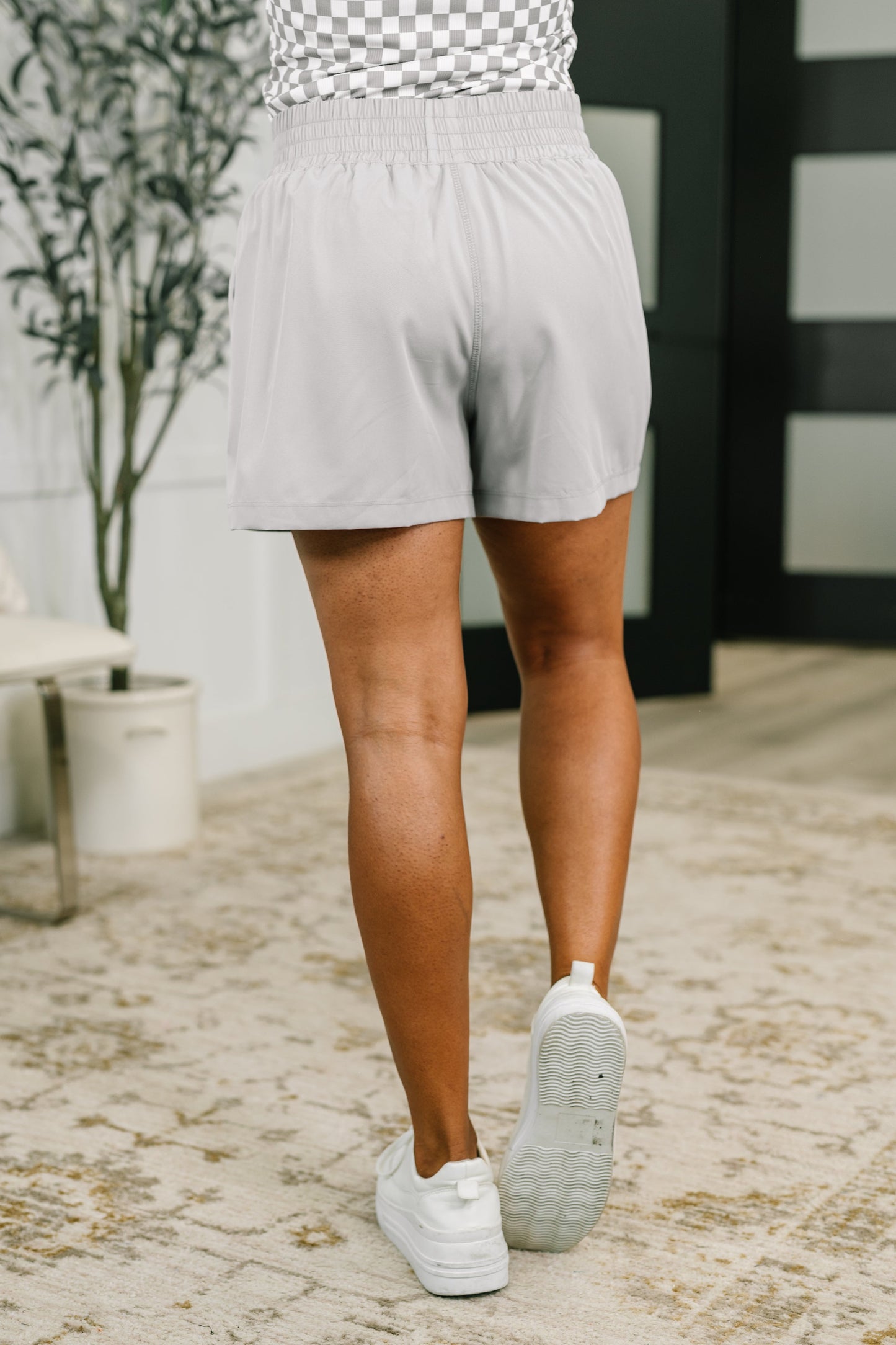 Person wearing light gray shorts and white sneakers on a stone path.