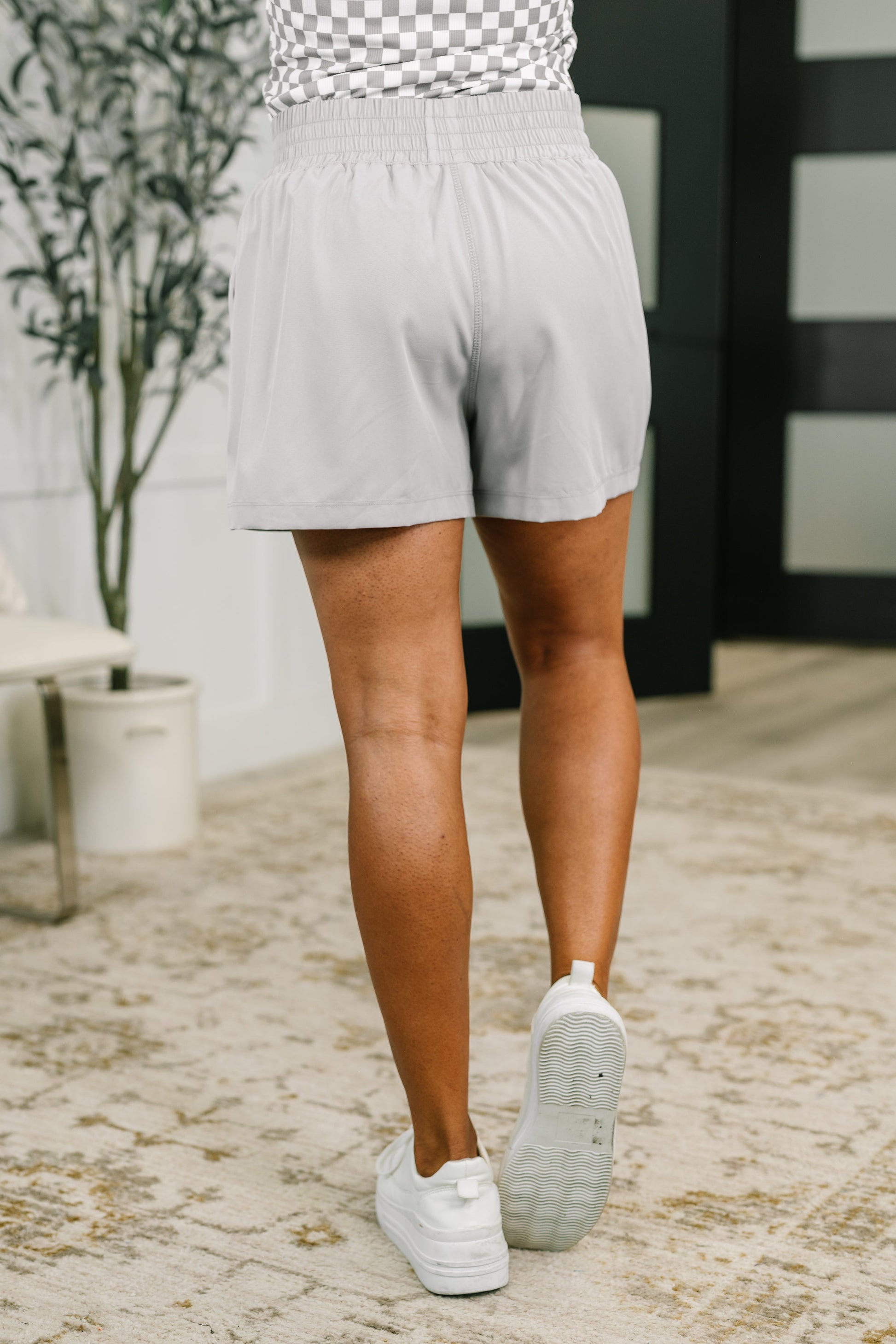 Person wearing light gray shorts and white sneakers on a stone path.