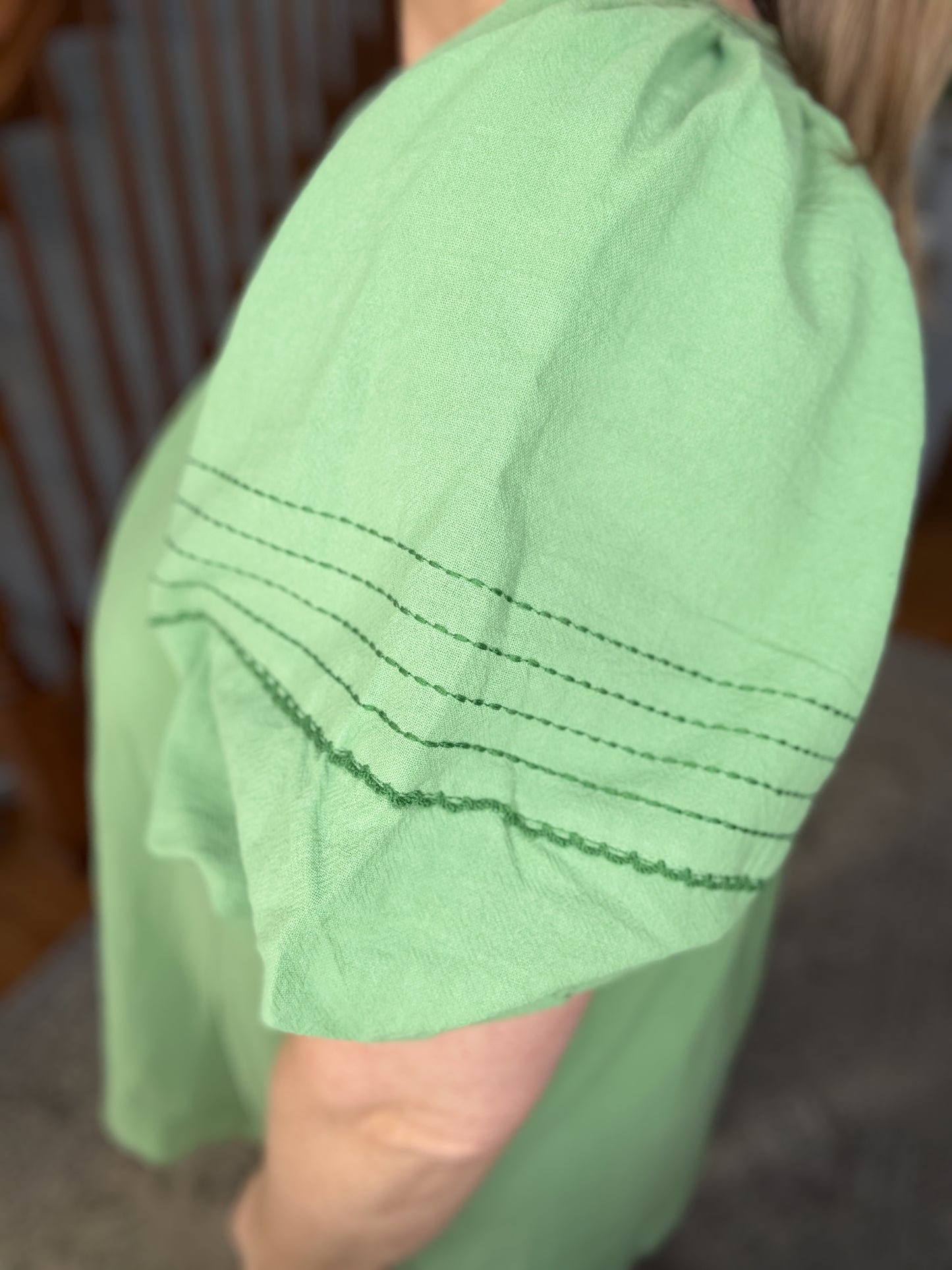 Close-up of a green fabric with stitching detail, held by a person.