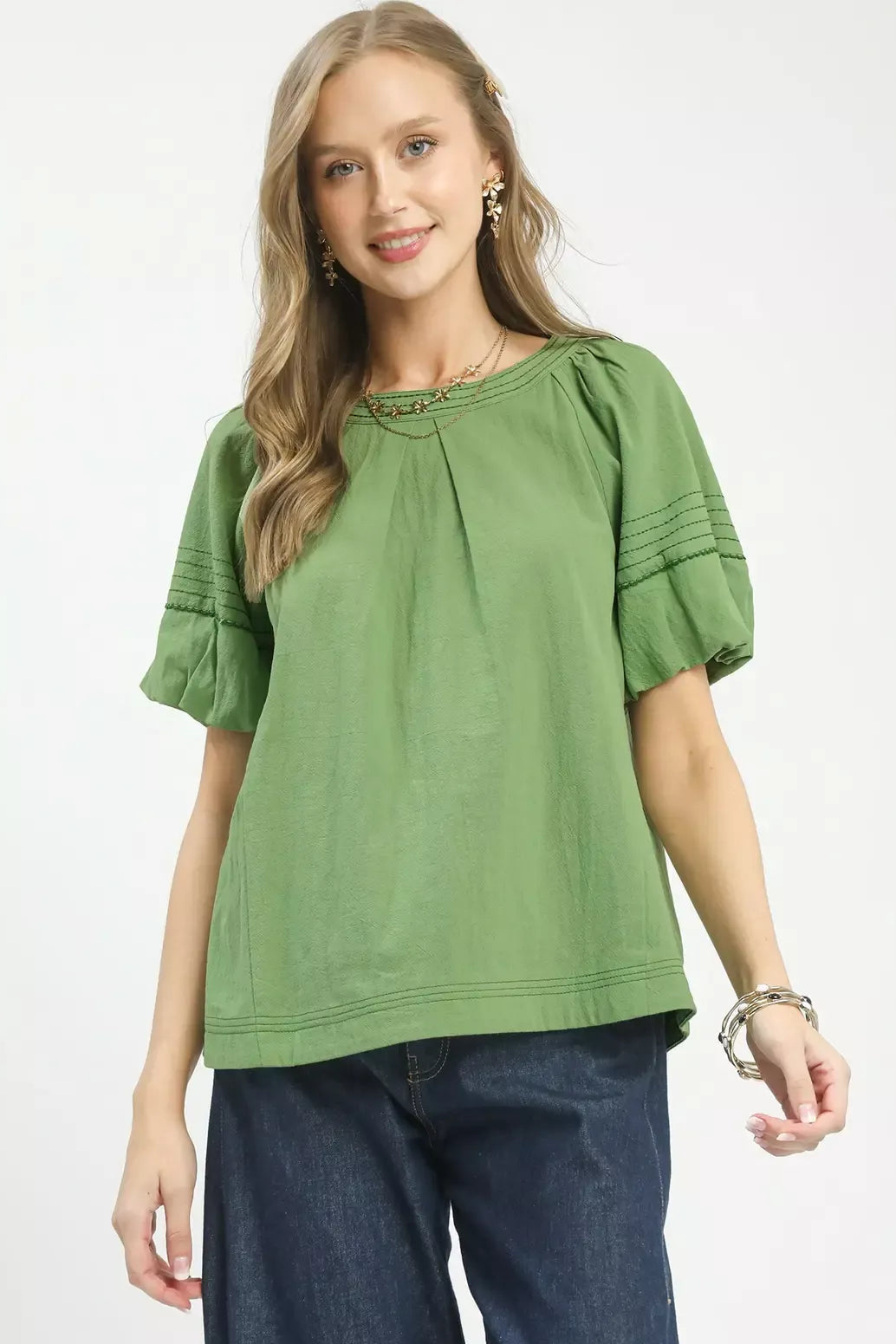 Woman wearing a green blouse with ruffled sleeves on a white background