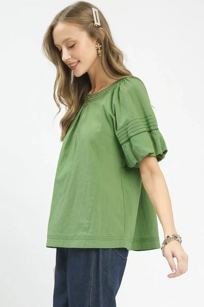 Woman wearing a green blouse with ruffled sleeves on a white background